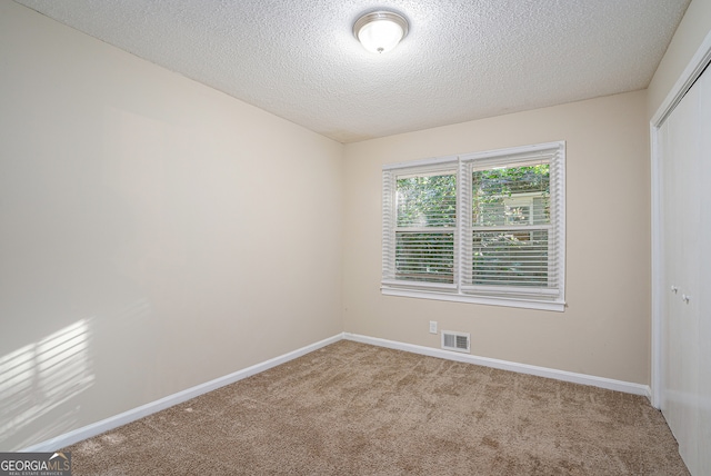 carpeted empty room featuring a textured ceiling