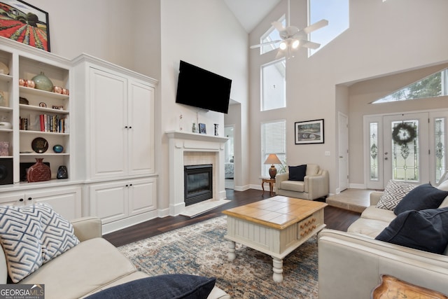 living room with high vaulted ceiling, ceiling fan, a tile fireplace, and dark hardwood / wood-style floors