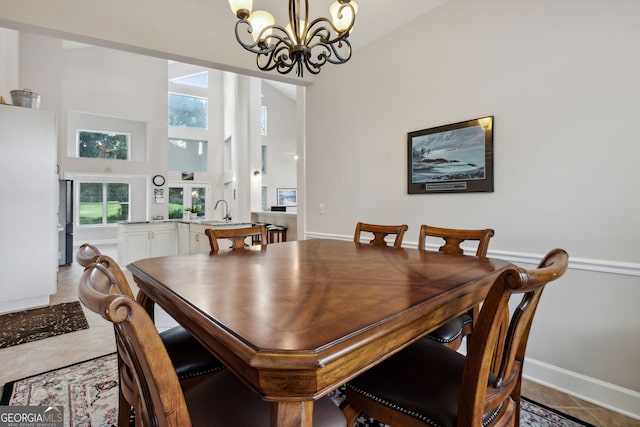 tiled dining area featuring a towering ceiling and a notable chandelier