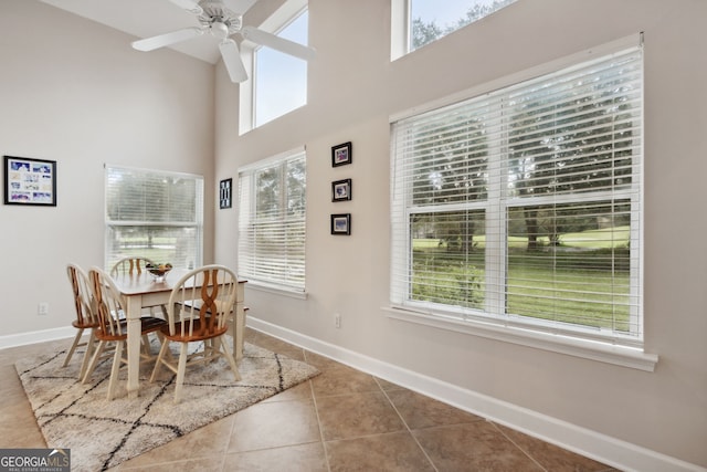 dining space featuring tile patterned flooring, a towering ceiling, and ceiling fan