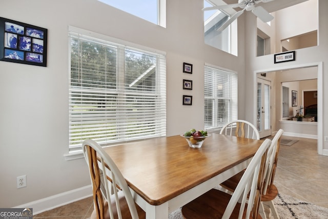 dining space with ceiling fan, light tile patterned floors, a high ceiling, and a healthy amount of sunlight