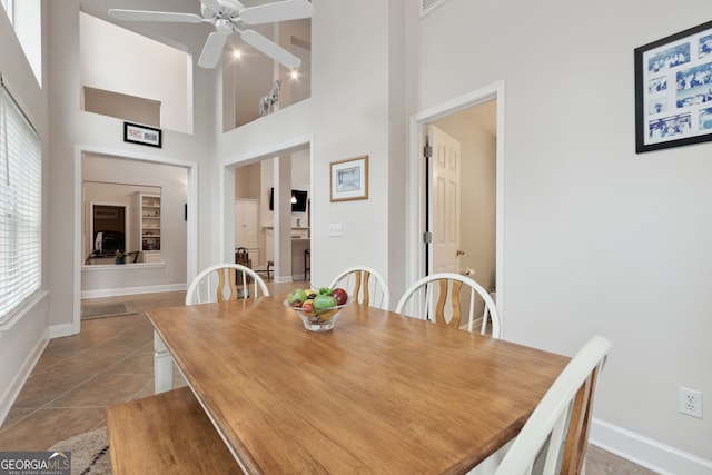 tiled dining space featuring a high ceiling and ceiling fan