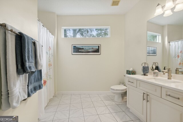 bathroom featuring vanity, tile patterned flooring, a healthy amount of sunlight, and toilet