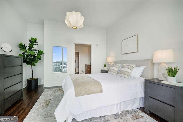 bedroom with connected bathroom and dark hardwood / wood-style flooring