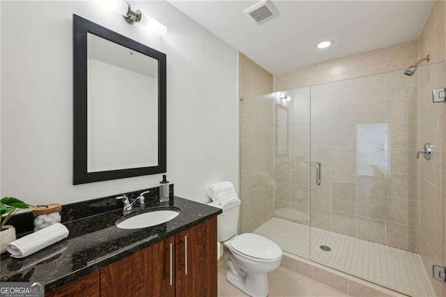 bathroom featuring tile patterned floors, a shower with door, vanity, and toilet