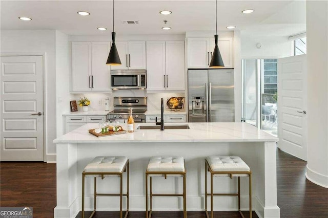 kitchen with sink, dark wood-type flooring, white cabinetry, appliances with stainless steel finishes, and light stone countertops