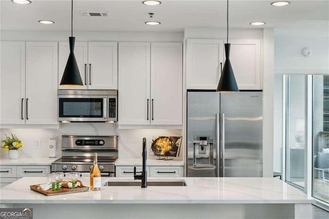 kitchen with decorative light fixtures, appliances with stainless steel finishes, sink, and white cabinetry