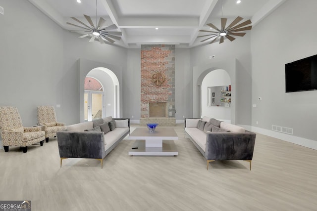 living room featuring beamed ceiling, light hardwood / wood-style floors, and a high ceiling