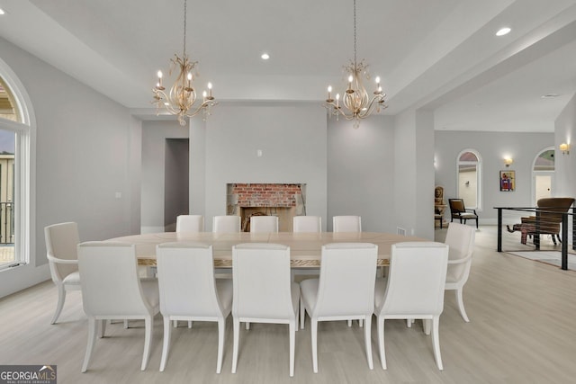 dining area with light wood-type flooring, a fireplace, and a chandelier