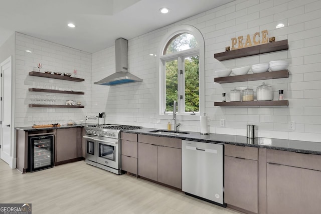 kitchen featuring sink, stainless steel appliances, wall chimney range hood, wine cooler, and light hardwood / wood-style flooring