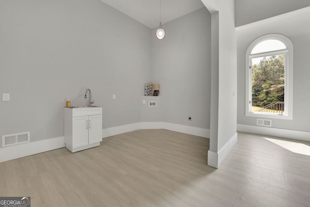 clothes washing area featuring cabinets, sink, and light hardwood / wood-style flooring