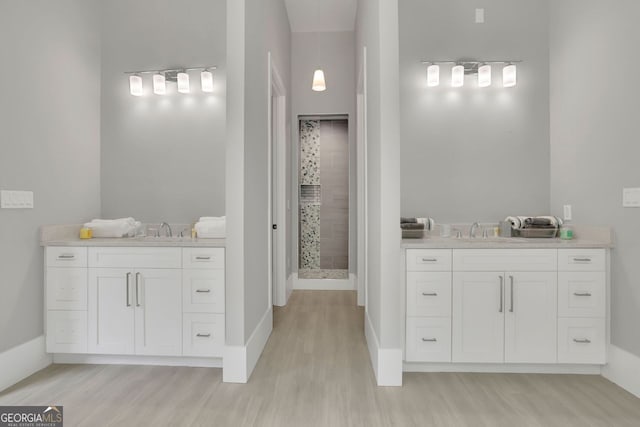 bathroom with hardwood / wood-style floors, vanity, and tiled shower