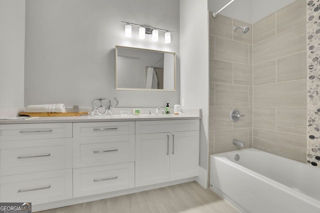 bathroom featuring hardwood / wood-style flooring, tiled shower / bath combo, and vanity