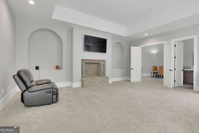 living area featuring light colored carpet and a brick fireplace