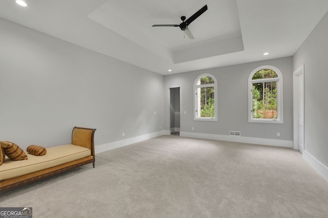 unfurnished room featuring light colored carpet, a raised ceiling, and ceiling fan