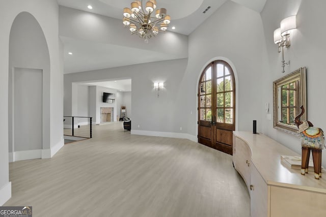 entrance foyer with light hardwood / wood-style flooring, high vaulted ceiling, a chandelier, and french doors