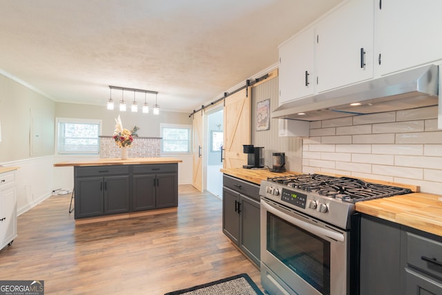 kitchen with a barn door, white cabinets, butcher block counters, and stainless steel gas range