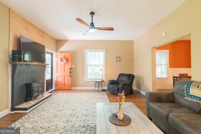 living room with a wood stove, ceiling fan, and wood-type flooring