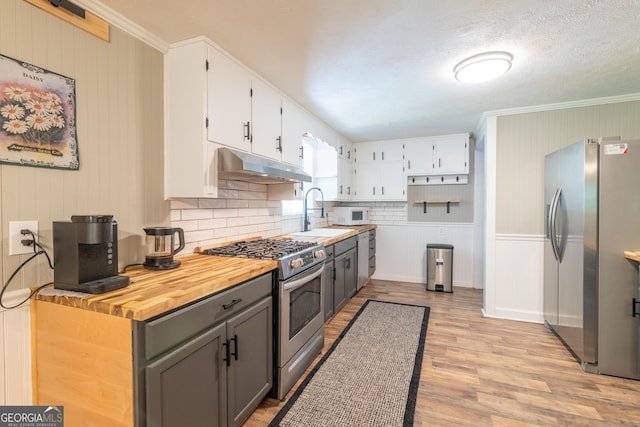 kitchen with gray cabinetry, sink, stainless steel appliances, decorative backsplash, and light wood-type flooring