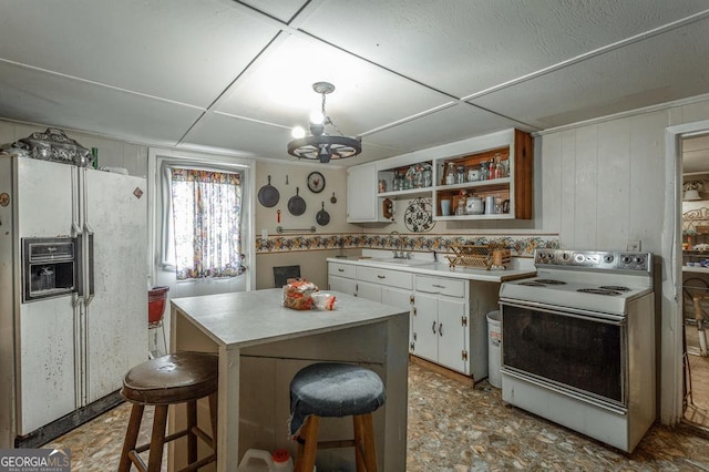 kitchen featuring white cabinetry, white appliances, pendant lighting, an inviting chandelier, and sink