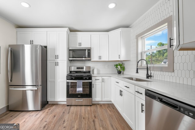 kitchen featuring light hardwood / wood-style floors, sink, white cabinets, decorative backsplash, and stainless steel appliances