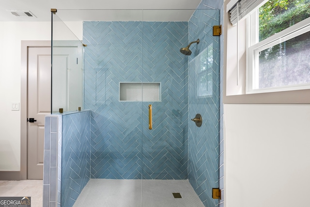 bathroom with tile patterned floors, a shower with door, and a healthy amount of sunlight