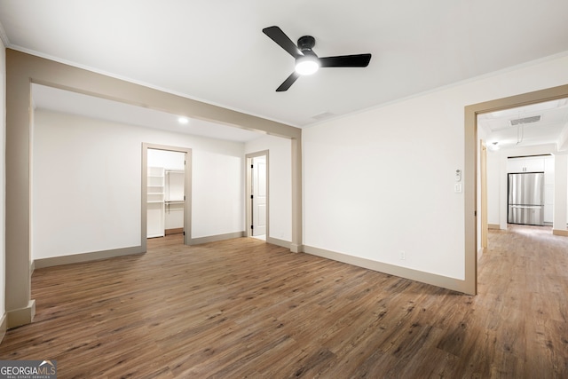 unfurnished bedroom with a spacious closet, ceiling fan, hardwood / wood-style floors, and stainless steel refrigerator