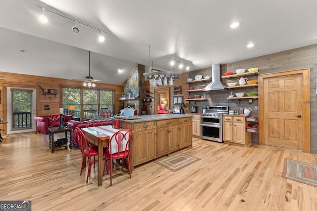 kitchen with open shelves, range with two ovens, lofted ceiling, wood walls, and wall chimney range hood