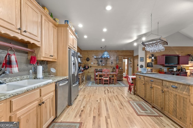 kitchen with light brown cabinets, light wood-style flooring, stainless steel appliances, decorative backsplash, and wood walls