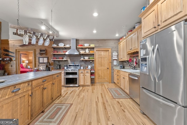 kitchen featuring open shelves, wall chimney range hood, light wood-style flooring, stainless steel appliances, and a sink