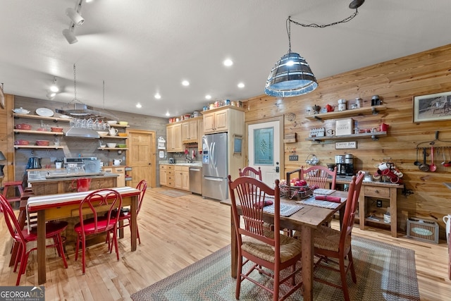 dining space featuring wooden walls, recessed lighting, rail lighting, and light wood-style floors