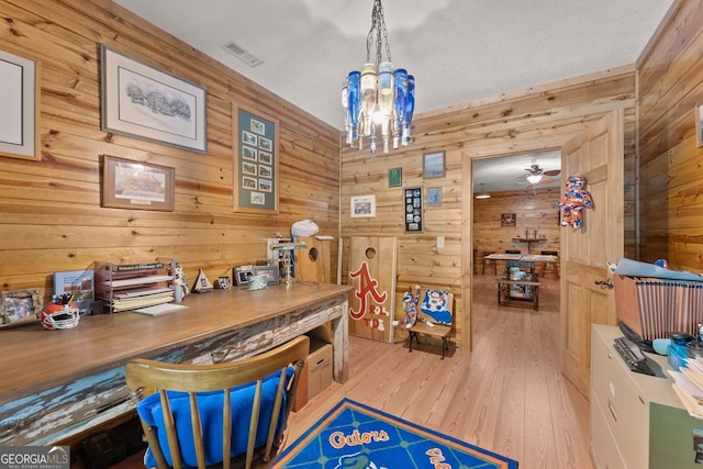 office area with visible vents, a textured ceiling, wood finished floors, wooden walls, and a chandelier