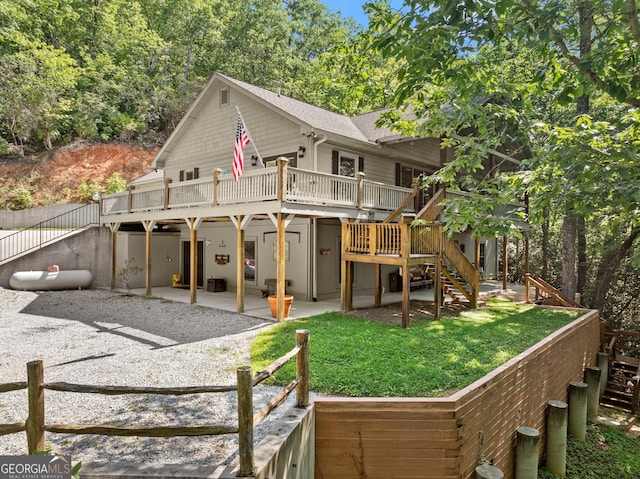 rear view of house featuring stairway, a lawn, a wooden deck, and a patio