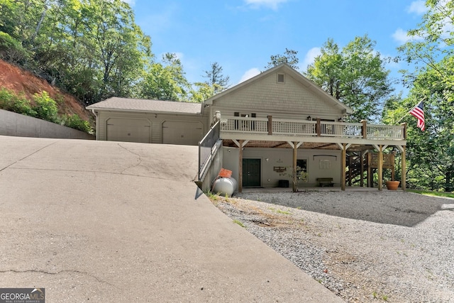 view of front facade featuring a deck, concrete driveway, stairs, and a garage