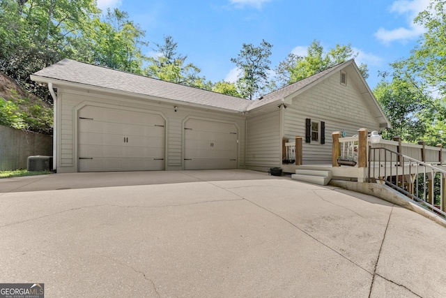 exterior space featuring driveway, central AC, fence, roof with shingles, and an attached garage