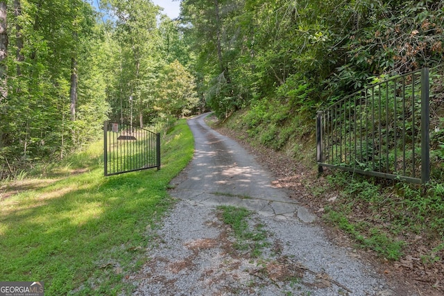 view of road with a gated entry, a view of trees, and a gate