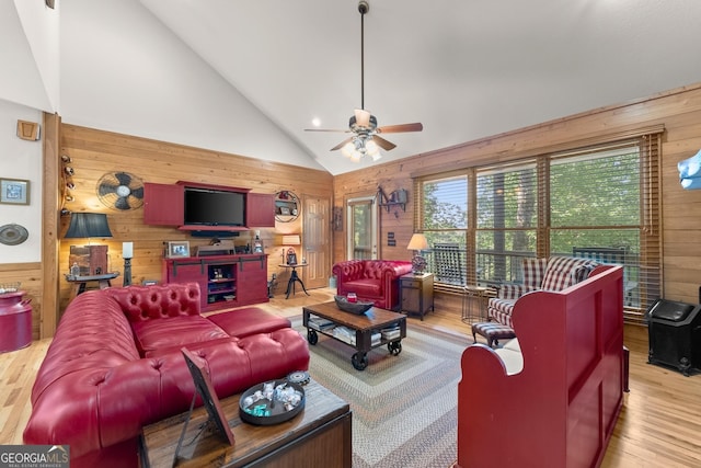 living room with wood walls, high vaulted ceiling, a ceiling fan, and wood finished floors