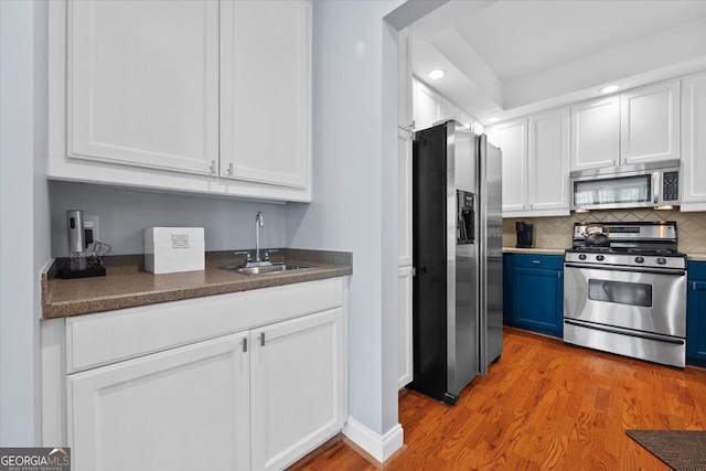 kitchen with light wood-type flooring, sink, white cabinetry, stainless steel appliances, and blue cabinetry