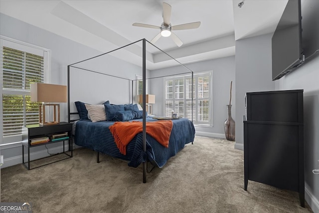 carpeted bedroom featuring ceiling fan and a tray ceiling