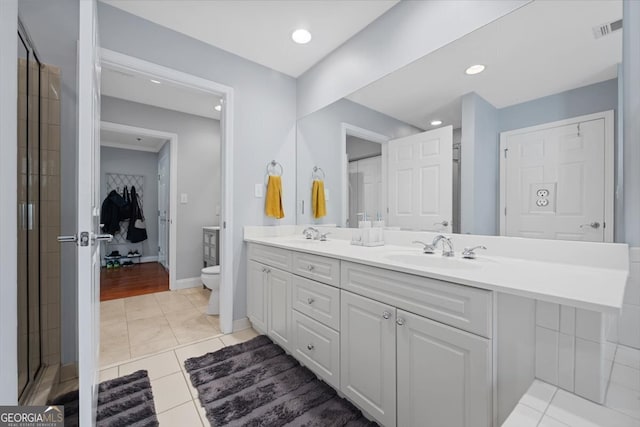 bathroom with a shower with door, vanity, toilet, and tile patterned floors