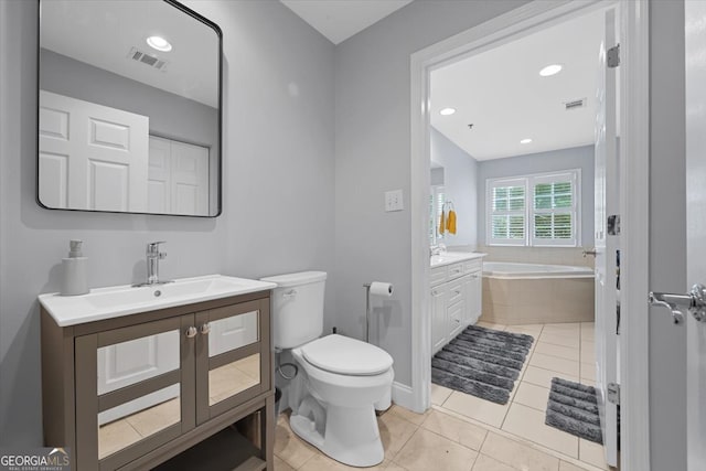 bathroom with vanity, tile patterned flooring, a relaxing tiled tub, and toilet