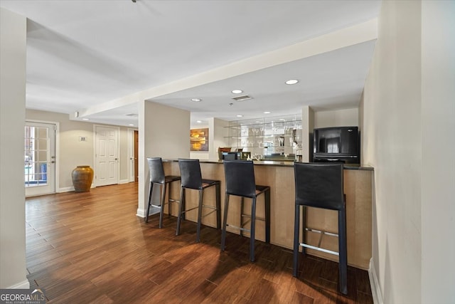 kitchen with kitchen peninsula, white cabinetry, dark hardwood / wood-style flooring, and a breakfast bar