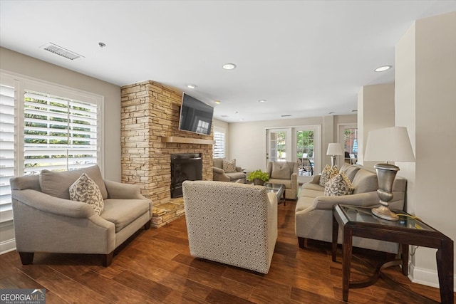 living room featuring a stone fireplace and dark hardwood / wood-style floors