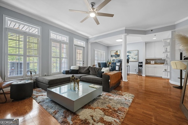 living room with ceiling fan, crown molding, ornate columns, and wood-type flooring