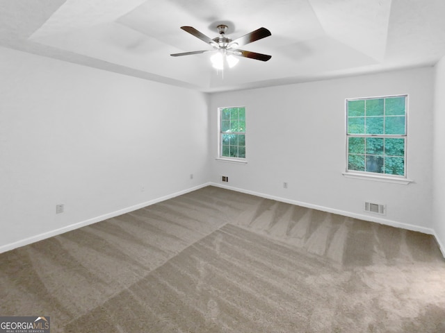 carpeted spare room featuring ceiling fan and a raised ceiling