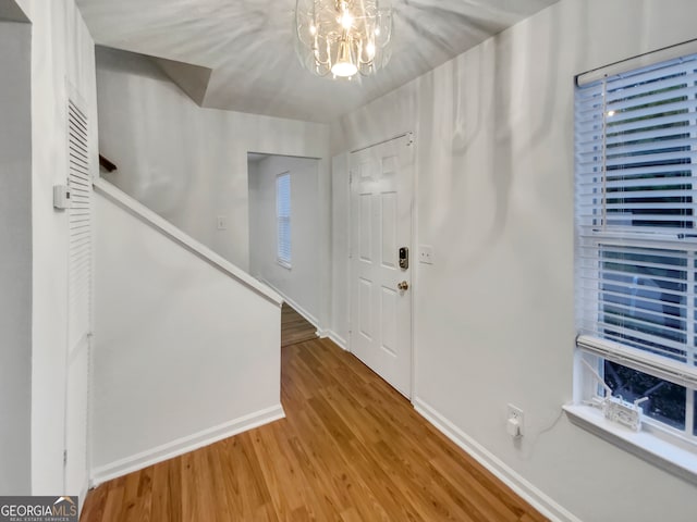 foyer entrance featuring wood-type flooring and a chandelier