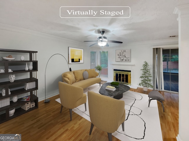 living room featuring wood-type flooring, crown molding, and ceiling fan