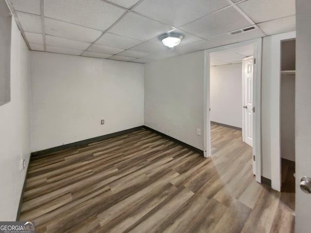 basement with a drop ceiling and dark hardwood / wood-style flooring