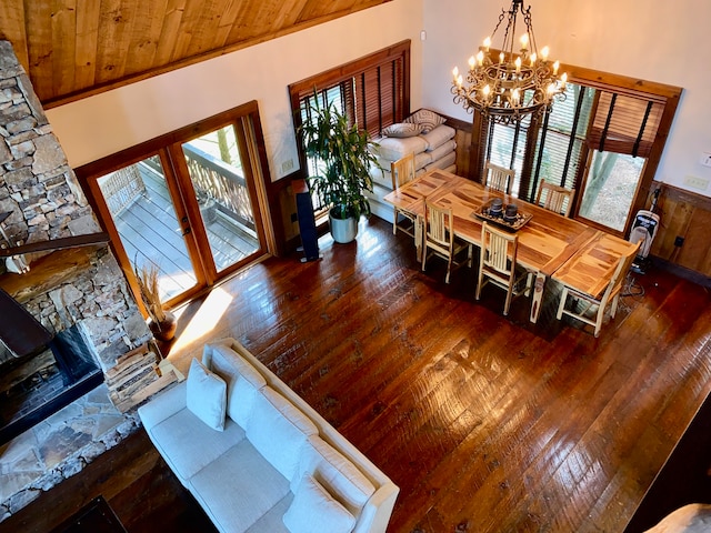 interior space featuring wood-type flooring, a stone fireplace, a chandelier, high vaulted ceiling, and wooden ceiling