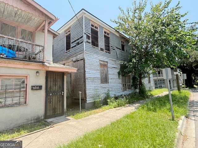 view of front of home featuring a balcony and a front lawn